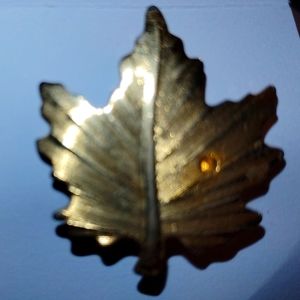 Brass toned maple leaf broach with yellow stone.